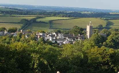 Dartmoor village with hills and church tower with flag