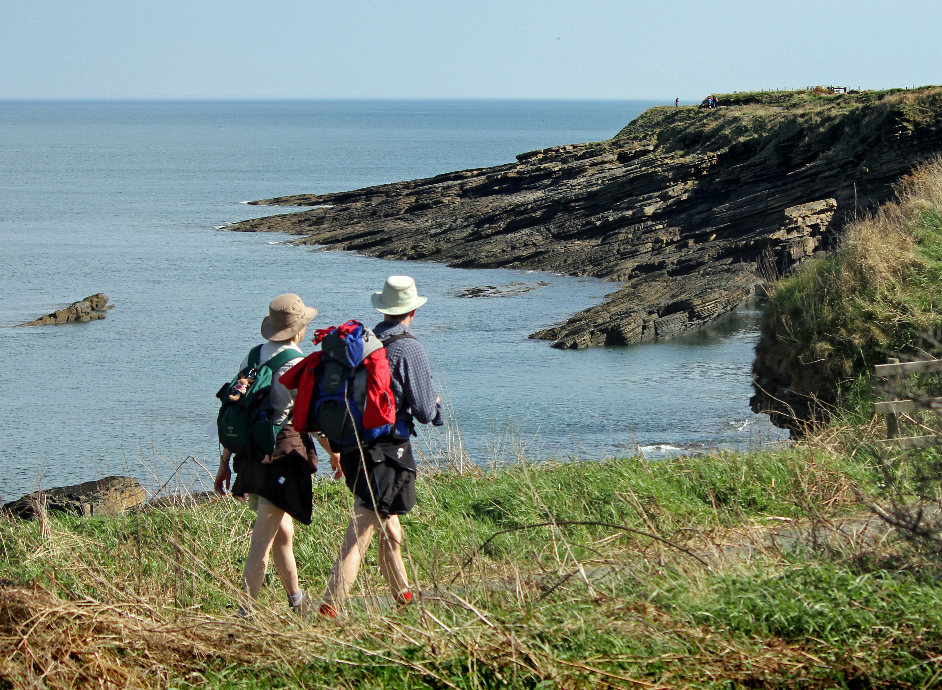Couple walking on coastal path overlooking sea and cliffs Northumberland