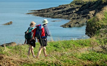 Couple walking on coastal path overlooking sea and cliffs Northumberland