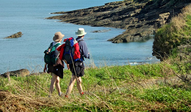 Couple walking on coastal path overlooking sea and cliffs Northumberland