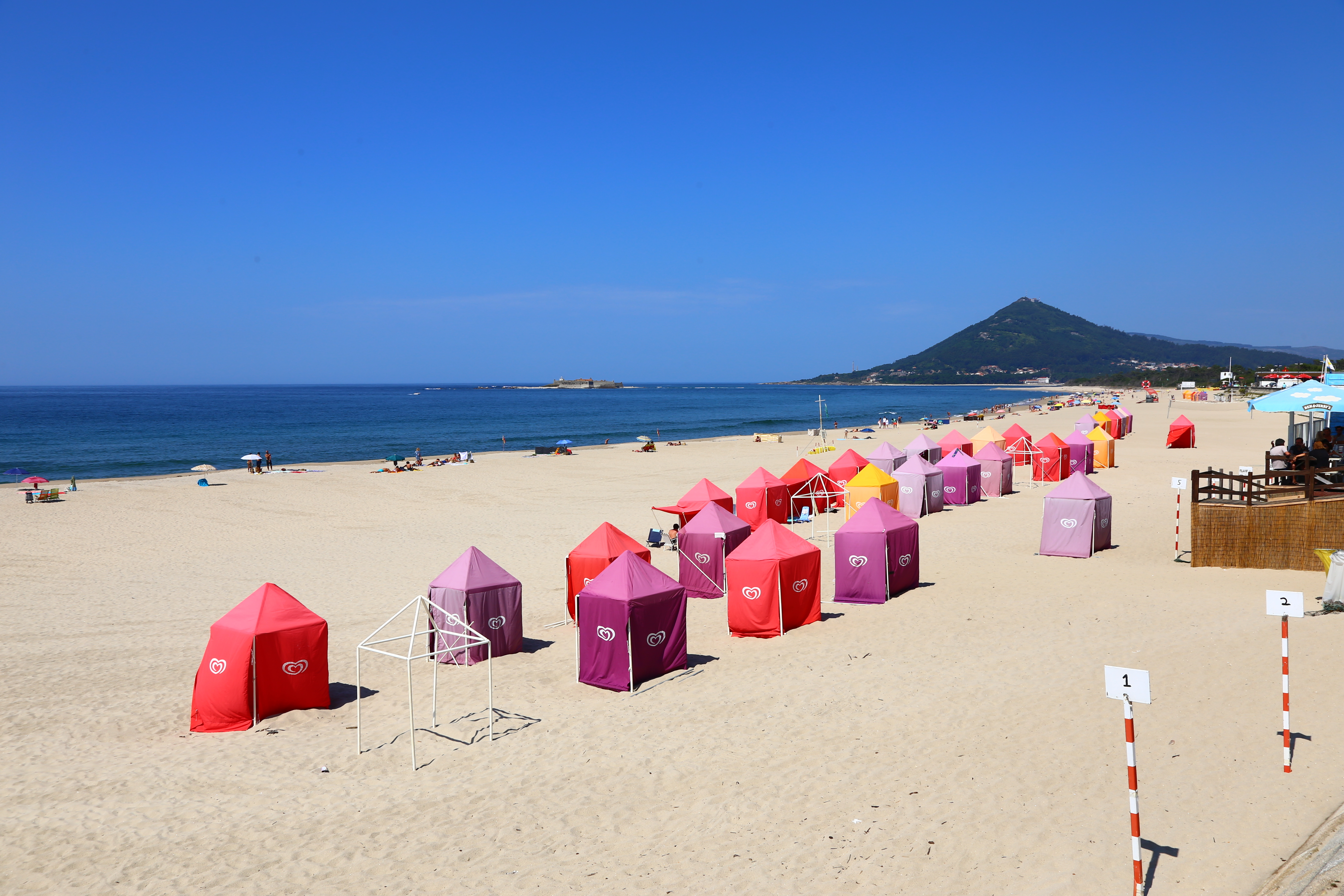 Wide sandy beach with red and pink sun huts
