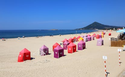 Wide sandy beach with red and pink sun huts