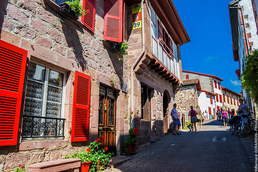 Stone houses with red shutters in a narrow street in the French Basque country