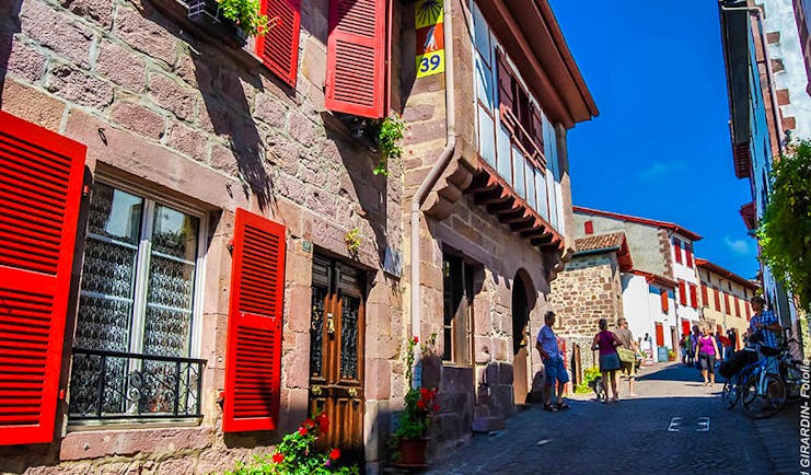 Stone houses with red shutters in a narrow street in the French Basque country