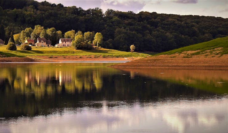 Lake in Burgundy with wooded hills and house in field behind