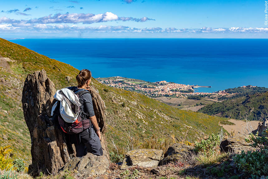 Walker on hillside overlooking coast with blue sea in distance