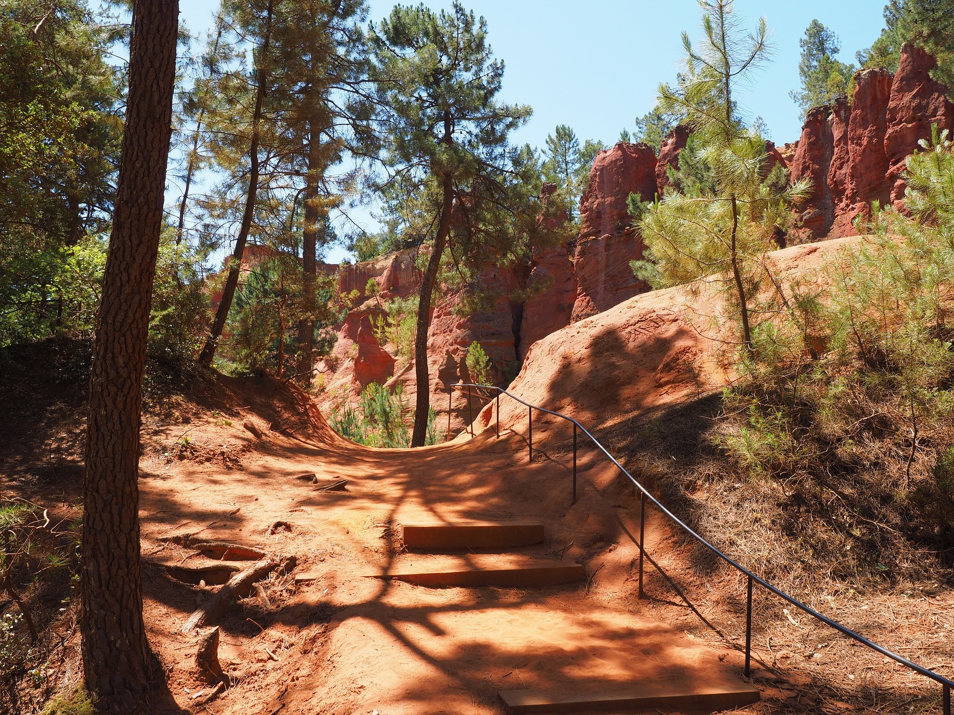 Path on red soil with trees and cliffs