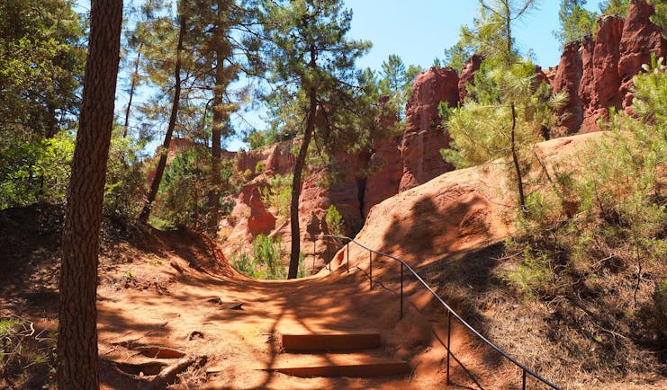Path on red soil with trees and cliffs